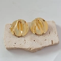 Dettaglio macro di orecchini dorati a martello irregolare su pietra di travertino beige - Oro (A-418)