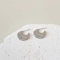 Dettaglio degli orecchini in argento a forma di C con finitura martellata unica - Argento