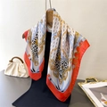 Detailed close-up of chain print silk scarf with leopard patterns and red hand-rolled edges - Orange