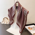 Detailed view of dark red polka dot silk scarf draped over a white ribbed top - Brown