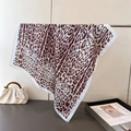 Macro detail of leopard print silk scarf showing white satin edges and smooth drape - White Border