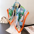 Elegant silk-like square scarf with horse and chain print over a casual outfit - Green