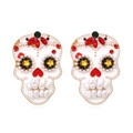 Exaggerated skull earrings with colorful crystals and pearl teeth on white background - Gold