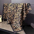 Detailed drape of a black and gold tiger pattern silk scarf on a metal rack display - 90x90cm / Black