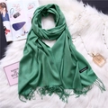 Detail of green cashmere scarf with fringe edges and label on white plush background - Fruit Green (FYR150-26)