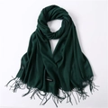 Close-up of a soft forest green cashmere scarf with fine tassels and fabric label - Dark Green