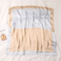 Detail view of a luxury light blue and champagne gold color-block square silk scarf - Light Blue and Champagne Gold