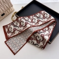 Close-up of paisley pattern silk scarf with red edges on a dark metal tray display - Red White Black Paisley Style (LJ21-H291) / 145x12cm