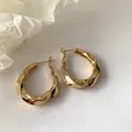 Nahaufnahme goldener gedrehter Creolen mit unregelmäßigem geometrischem Design und Glanz - Gedrehte Geometrische Ohrringe (D316) / Gold