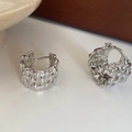 Detailed close-up of silver C-shaped chunky earrings with woven texture and polished finish - Silver