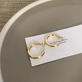 Dettaglio di orecchini a cerchio dorati su carta bianca con sfondo in ceramica grigia - Oro (F205)