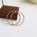 Detailed view of polished large gold hoop earrings with pin buckle on dark wood stand - Gold (4cm)