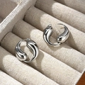 Macro detail of silver teardrop earrings with high-polish finish in a beige linen box - Silver