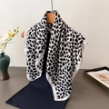 Elegant black and white leopard print scarf draped on a wooden hanger with knitwear - White
