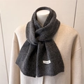 Dettaglio di una sciarpa in maglia grigio scuro in misto lana con etichetta materiale - grigio scuro
