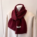 Close-up of a dark red wool blend scarf with a luxury brand label on a beige coat - 164x22cm / Jujube Red (WT282-6)