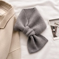 Detalle de bufanda de punto gris con diseño cruzado junto a un abrigo de lana suave - Gris