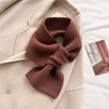 Detailed texture of thick dark brown knitted scarf with a crossover design on a wool coat - Brown