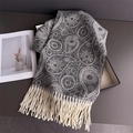 Detail eines grauen Kaschmirschals mit Paisley-Muster und dicken hellen Quasten - Jacquard Grau