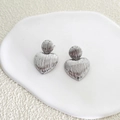 Detailed view of silver heart earrings with vertical stripes on a white ceramic tray - 3.6*2.5cm / Silver
