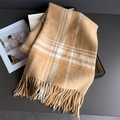 Close-up of thick plaid scarf with long tassels inside a black gift box packaging - Camel