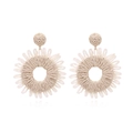 Handmade raffia sunflower earrings with bohemian woven texture on white background - Beige