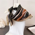 Detail eines Seidenschals mit Reitsportmuster und Kettenmotiven an einer Schneiderpuppe - 68*68cm / Braun