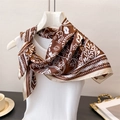 Close-up of silk scarf with paisley floral print tied elegantly on a white top - Brown (FG87-1)