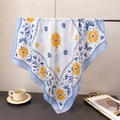 Nahaufnahme von Seidenschal mit gelben Gänseblümchen und blauem Rand am Kleiderbügel - Blau