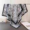 Detail of bamboo print silk scarf showing smooth texture and elegant drape on a rack - 90x90cm / Black
