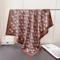 Dettaglio di un foulard in seta con stampa floreale bianca e drappeggio vicino borsa - Marrone