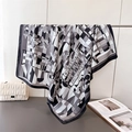 Detail of geometric floral silk scarf draped with luxury quilted bag and magazine - Black