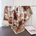 Detailed view of coffee floral silk scarf draped elegantly next to a fashion magazine - Brown