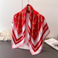 Elegant red silk-like scarf with gold chain print and striped border hanging on a rack - 90*90cm / Red