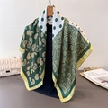 Detailed texture of green paisley and polka dot silk-like scarf draped on wooden hanger - Green