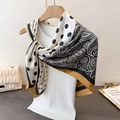 Detail of silk-like paisley scarf with polka dots draped on a minimal wooden hanger - Black