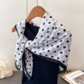 Dettaglio di sciarpa in seta geometrica a pois con motivo a lettera C su gruccia di legno - 90cm X 90cm / Bianco