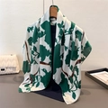 Dettaglio di sciarpa in raso con fiori verde scuro e nastro beauty appesa a una gruccia - 90x90cm / Verde