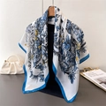 Elegant white silk scarf with blue butterfly and floral print hanging on a wooden hanger - Blue