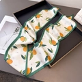 Detail of citrus print skinny silk scarf with dark green edges on elegant tray - Off-white Citrus Floral (Green Border)