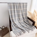 Detalle de chal de cachemira a cuadros con flecos sobre un sillón en ambiente cálido - Cuadros Grises (WT210-3)