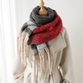 Detailed close-up of thick knit color-block scarf with long tassels on a beige coat - Red