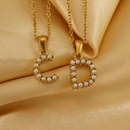Gros plan de colliers dorés avec pendentifs lettres C et D sertis de perles sur satin - Lettre A / Or