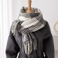 Close-up of black and white plaid scarf texture with fringe on wool coat display - White