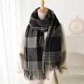 Close-up of black and white checkered scarf with fringe on a beige coat model - Black