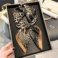 Elegante foulard in raso leopardato esposto su un vassoio nero con accessori di lusso - 70x70cm / Leopardo Caffè