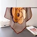 Elegant herringbone silk scarf with camellia flower pattern hanging on metal rack - Yellow