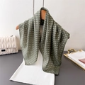 Elegant grey-green polka dot silk scarf hanging on a wooden hanger with knitted top - Green