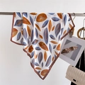 Elegant silk scarf with orange and blue leaf print hanging on a metal stand - Coffee Leaf Print / FG18-2 Coffee