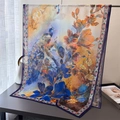 Detail view of large floral peacock print silk scarf draped elegantly on a metal rack - 180x70cm / Navy Blue